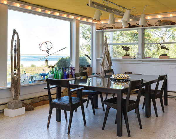 In the dining area, two black tables custom-built for MoMA’s opening in 1929 and discarded in the 1960s are pushed together and surrounded by chairs designed by Jens Risom, purchased by the couple in the 1950s. Throughout the room are Mabel’s driftwood, wire, and concrete assemblages, and part of her glass collection lines the window sill. | Photography by Jenny Gorman