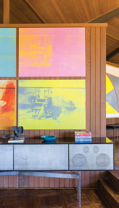 The couple has furnished the interior with favorite pieces from their extensive collections of contemporary art and mid-century design. Here Andy Warhol’s Electric Chair Suite hangs above a Craig Ellwood stereo—designed in 1961 for the Rosen House in Mandeville Canyon, Los Angeles—on which is a small bronze by Harry Bertoia, Untitled (Maquette for a Fountain). | Photography by Stephan Julliard