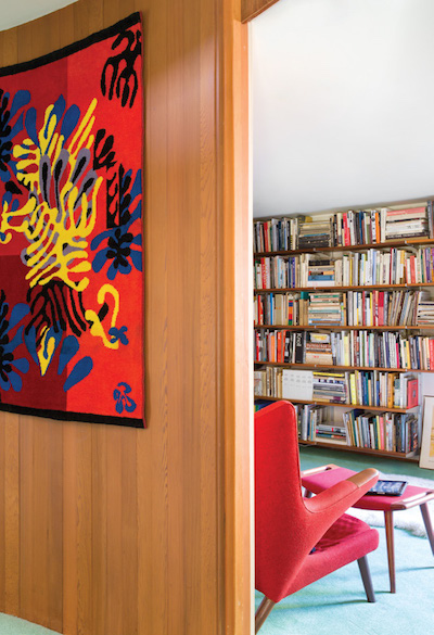 Outside the library hangs a Mimosa tapestry by Henri Matisse, which picks up the red of the Hans Wegner Papa Bear chair and ottoman in the room. | Photography by Stephan Julliard