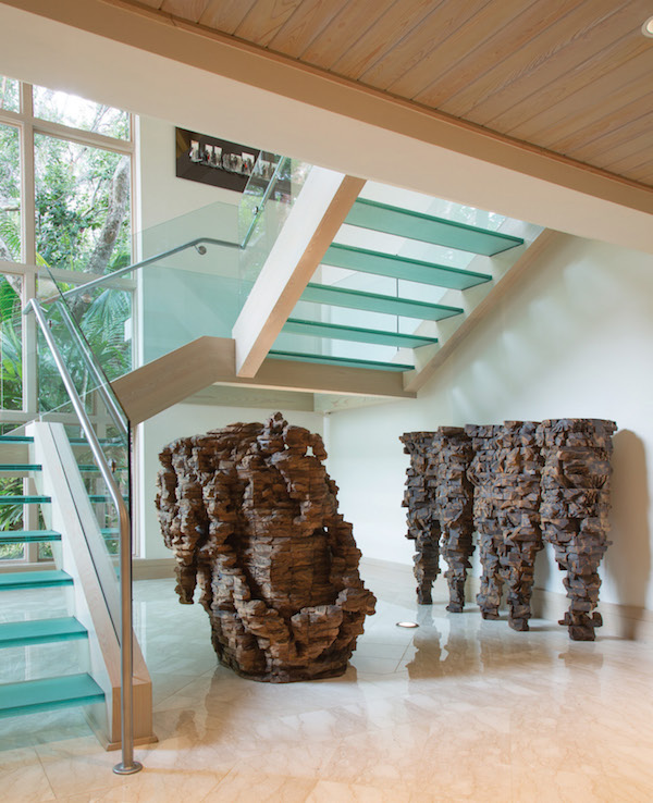 Two large-scale cedar and graphite sculptures by Ursula von Rydingsvard, Amelia and Five Cones, stand next to the dramatic glass staircase in the foyer of the main house.