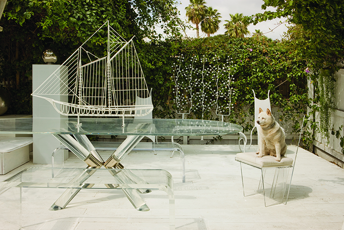 Patio of Jones’s residence, c. 2004. The Truss dining table from the Post line, c. 1970, in acrylic and chrome is flanked by a pair of Waterfall line benches, 1970, in acrylic. Jones’s dog Shyla sits on a Wisteria chair from the Blade line, designed for Tennessee Williams, 1968, in acrylic with upholstered cushion. The ship sculpture on the table is by Curtis Jeré. MARY E. NICHOLS PHOTO